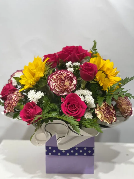 Mixed roses, sunflowers and carnation posy in a purple polka-dot gift box