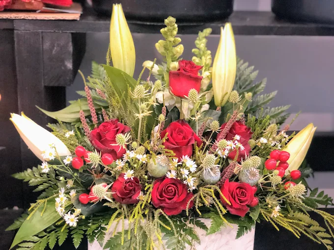 Red-rose and white-lily arrangement in a white pot on the shop counter